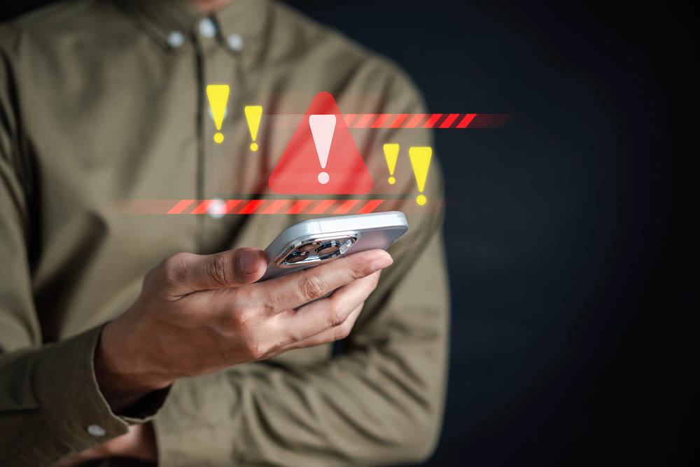 Holding a cell phone, warning symbols flashing in the air