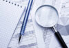 A magnifying glass and pen on charts and data