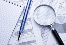 A magnifying glass and pen on charts and data