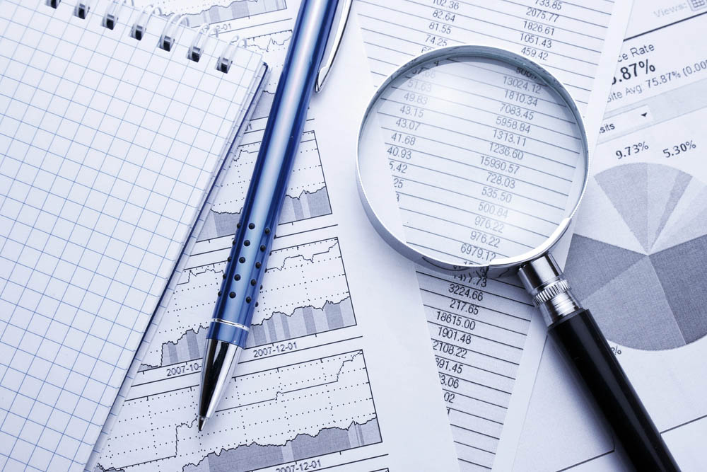 A magnifying glass and pen on charts and data