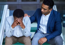 Shot of a young man comforting his peer on the steps