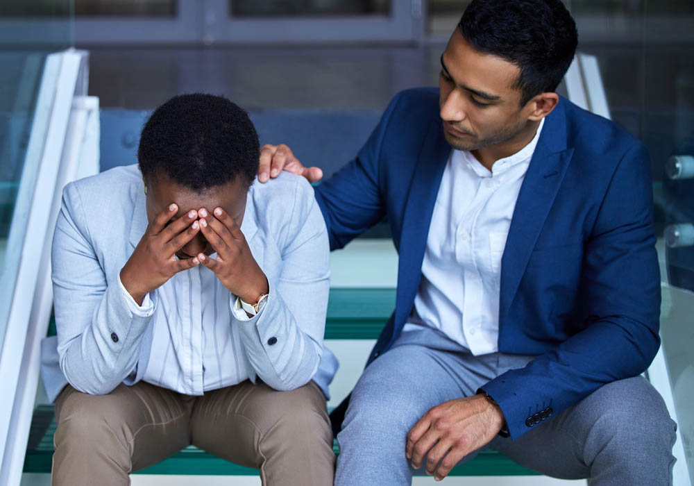 Shot of a young man comforting his peer on the steps