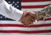 Soldier and politician shaking hands against flag of USA, closeup