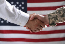 Soldier and politician shaking hands against flag of USA, closeup