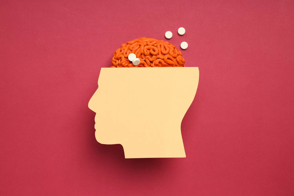 Paper head with brain and pills on red background