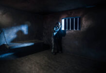 Miniature photography. Lonely man bathed in moonlight in a prison cell