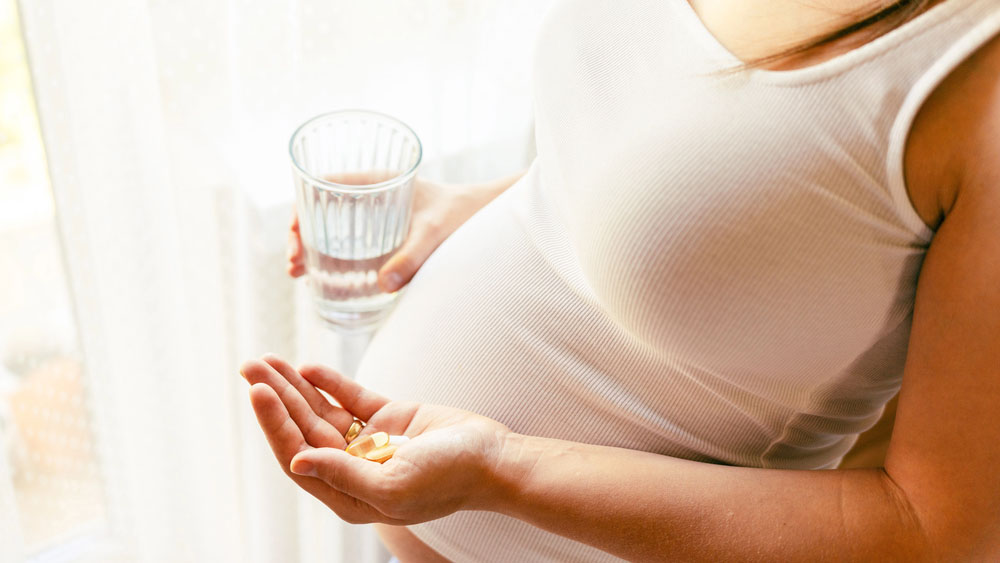 Supplements vitamins pill. Happy young pregnant woman holding supplement vitamin pill. Therapy, healthcare, motherhood concept