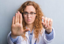 New NEJM Perspective on Antidepressants and Pregnancy Misses the Mark white professional woman holds a pill in one hand and makes a "stop" gesture with the other