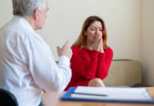 Psychiatric Force and Coercion Undermine Recovery A frustrated crying woman holds her palms over face at a session with a male psychologist
