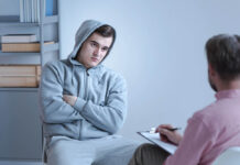 Are We Overlooking Homicidal Ideation in Psychiatry? An individual therapeutic session between a psychologist and a withdrawn troubled teenage boy sitting in a closed position with his arms crossed across his chest.