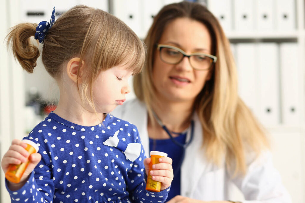 A child holds two pill bottles