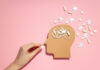 A Call for a Paradigm Shift in Schizophrenia Treatment: Reassessing Long-Term Antipsychotic Use and the Evidence for Psychosocial Interventions Illustration of hand feeding pill to head with puzzle pieces around it