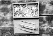 Getting Rid of the Pain Before Answering Its Questions: Psychiatry’s Damage to Self and Culture Pharmaceutical drugs pills and syringe vials in box on wooden background